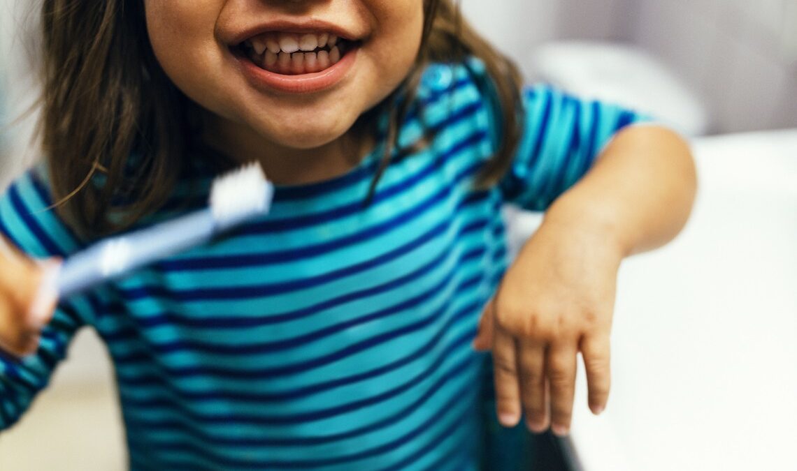 I 10 problemi dentali più comuni nei bambini e come prevenirli - bambina con spazzolino da denti che sorride