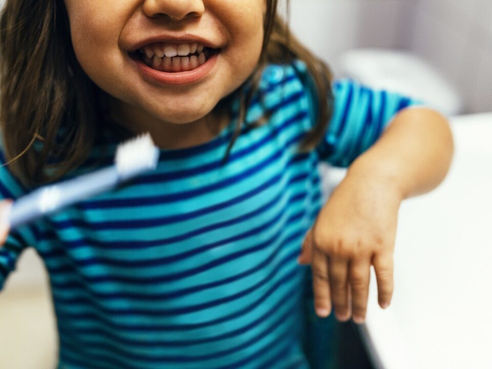I 10 problemi dentali più comuni nei bambini e come prevenirli - bambina con spazzolino da denti che sorride